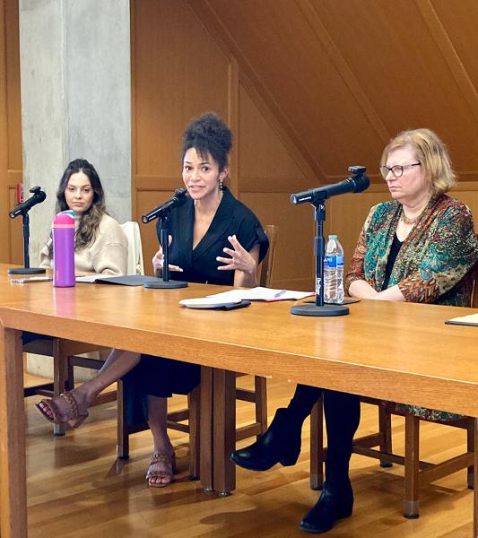 Panelists at table in conversation with one another