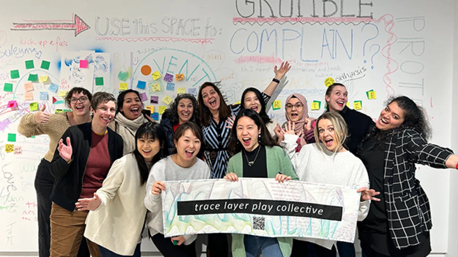 Group of artists hold sign that says trace layer play collective