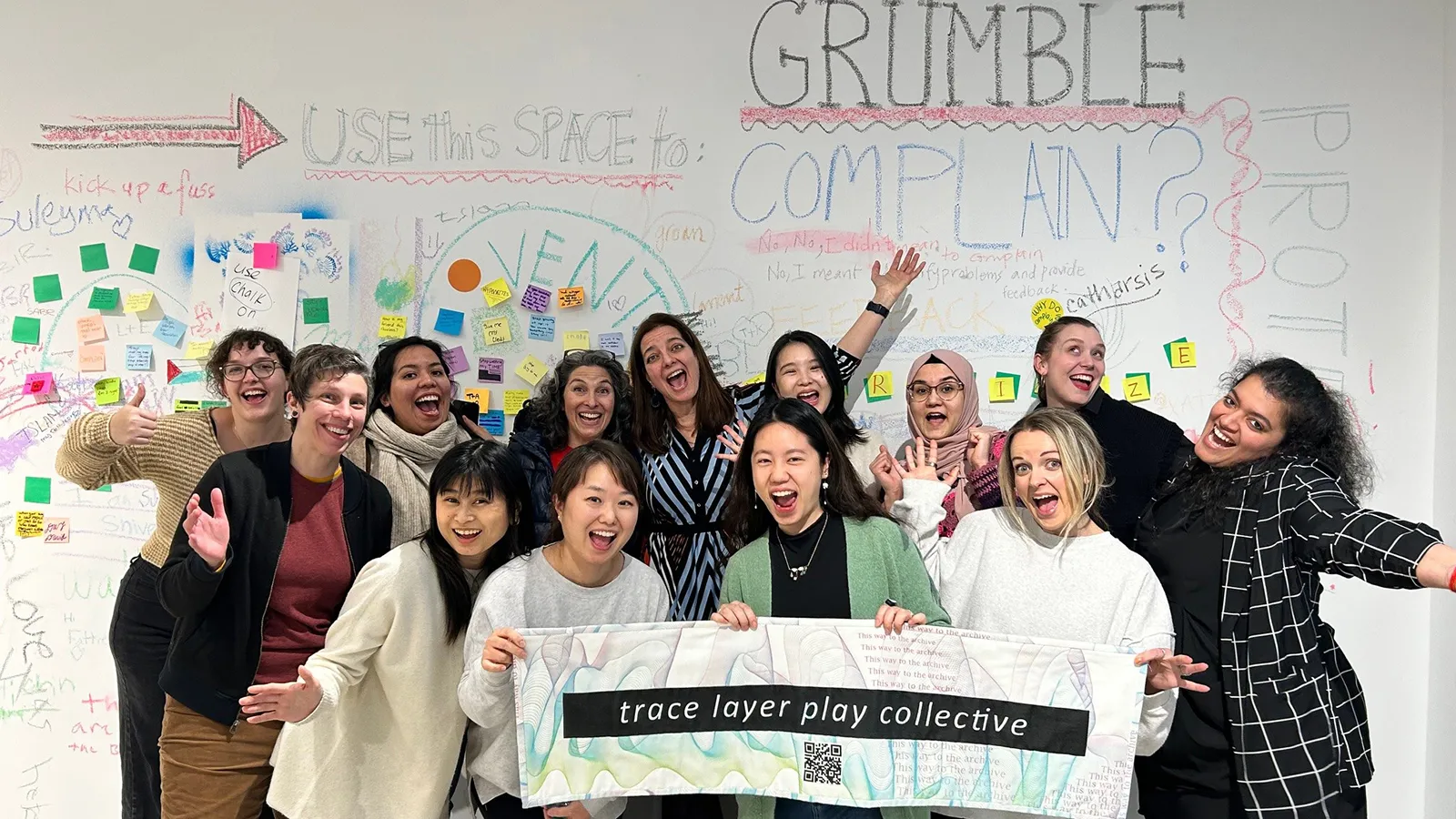 Group of artists hold sign that says trace layer play collective