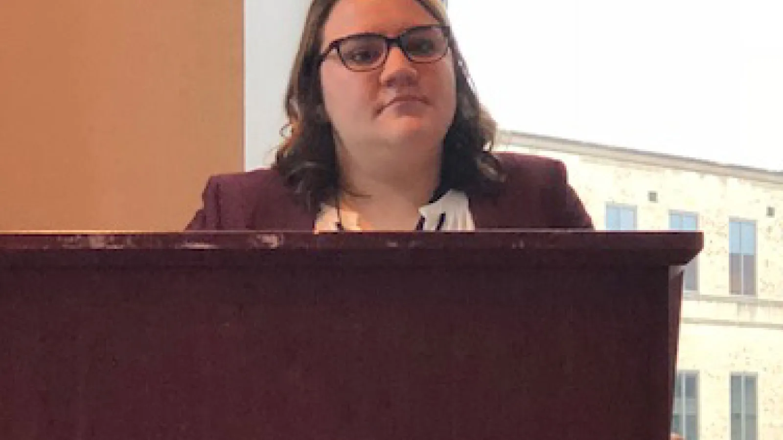 Allison Susor stands at a podium for her research presentation.