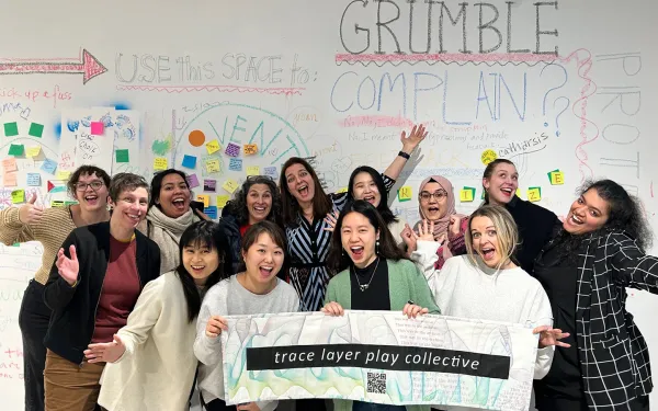 Group of artists hold sign that says trace layer play collective