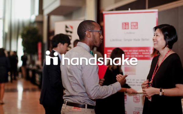 Student talking to employer at career fair with Handshake logo 