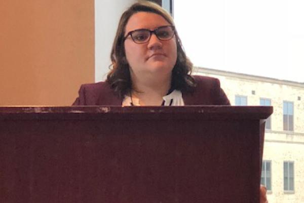 Allison Susor stands at a podium for her research presentation.