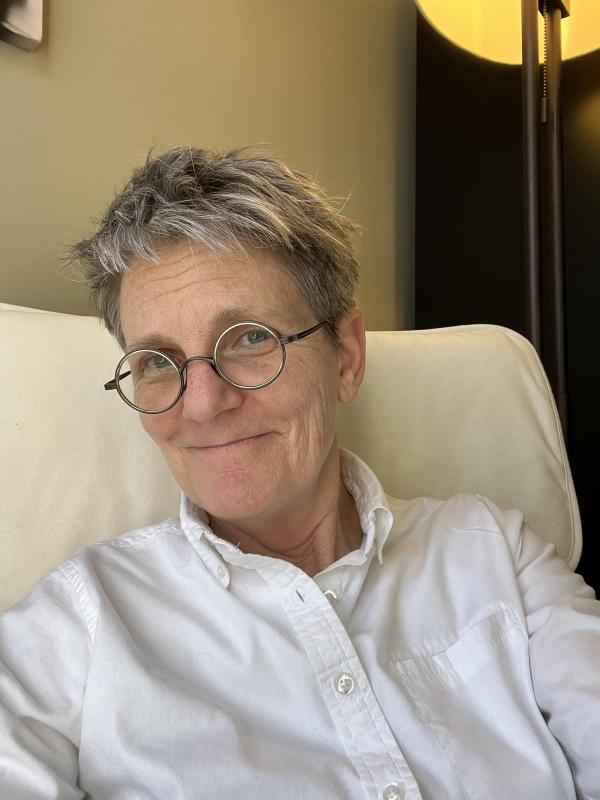 Photo of white woman with glasses smiling in a white chair
