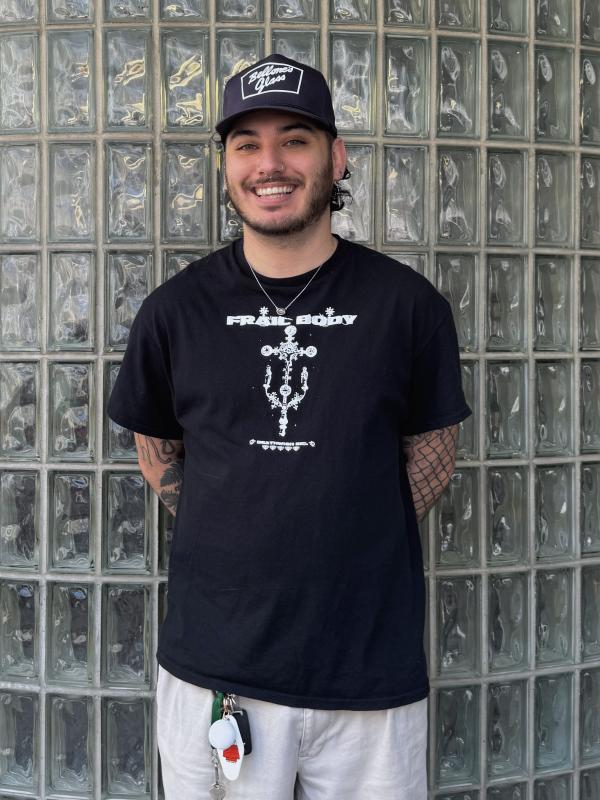 Portrait of Ian standing against a wall of glass block, smiling