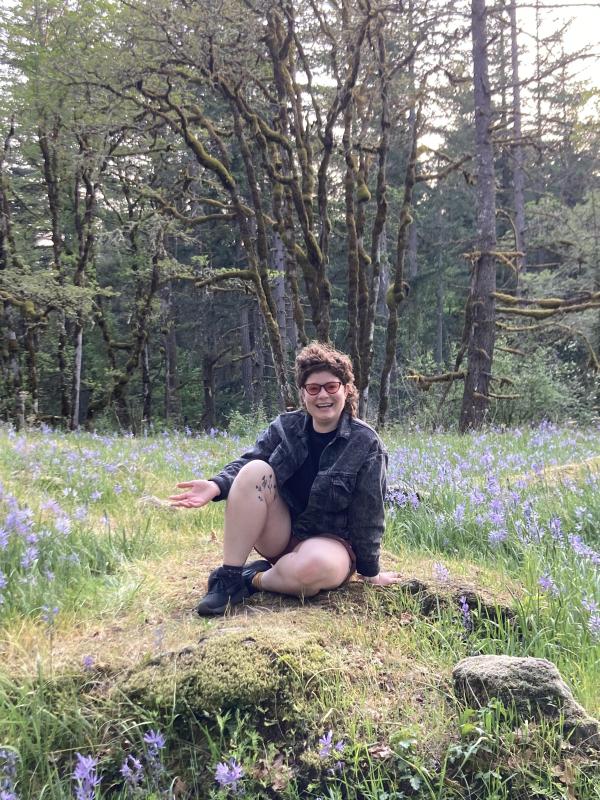 nico sits on a rock in a field of purple camus lilies